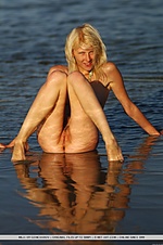 Wet, athletic body splashing and posing unihibitedbly in the lake.